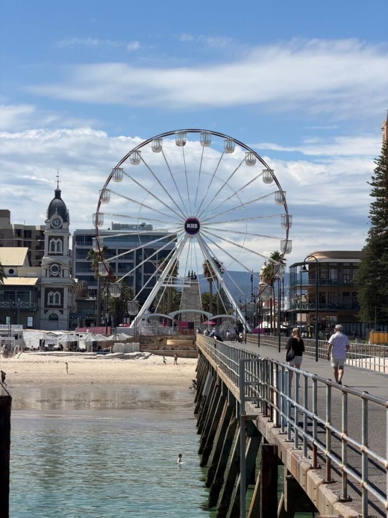 View of the Glenelg Ferris Wheel from the pier, showcasing beachside charm with a clear sky.
